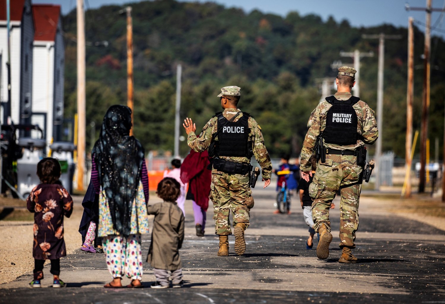 U.S. Military Police walk past Afghan refugees at the Village at Fort McCoy U.S. Army base, in Wisconsin, Sept. 30, 2021.